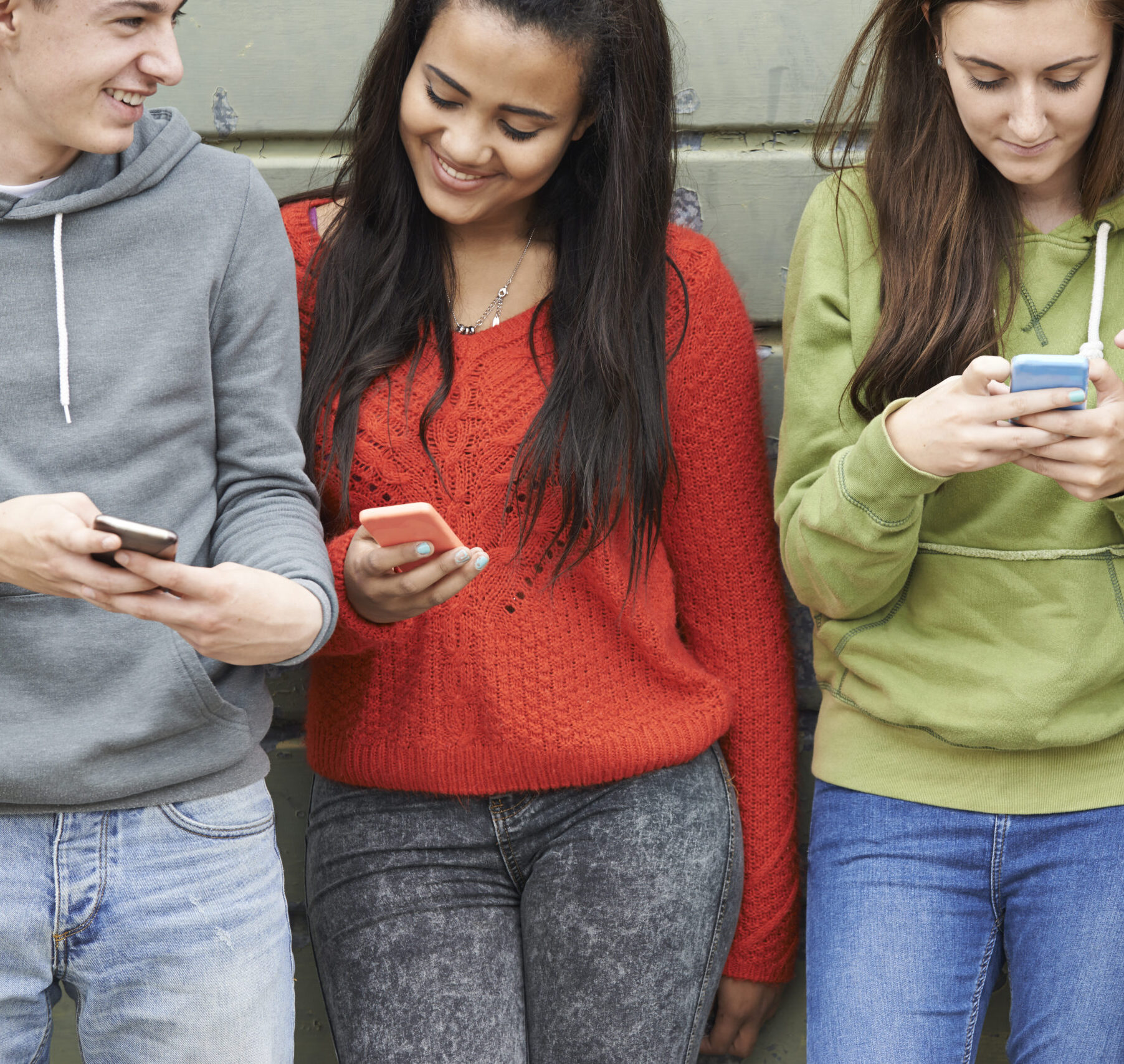 Group Of Teenagers Sharing Text Message On Mobile Phones Group Of Teenagers Sharing Text Message On Mobile Phones